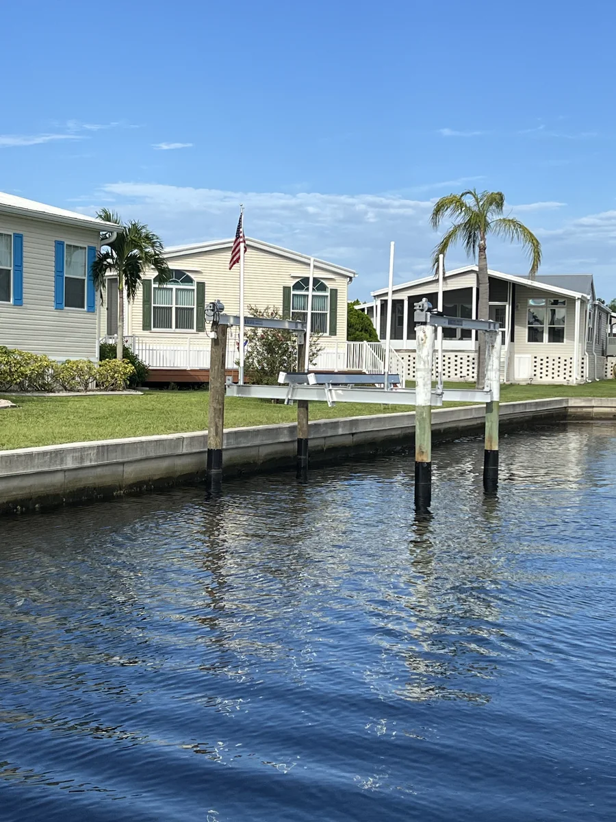 A residential canal with seawall, palms, and boat lift