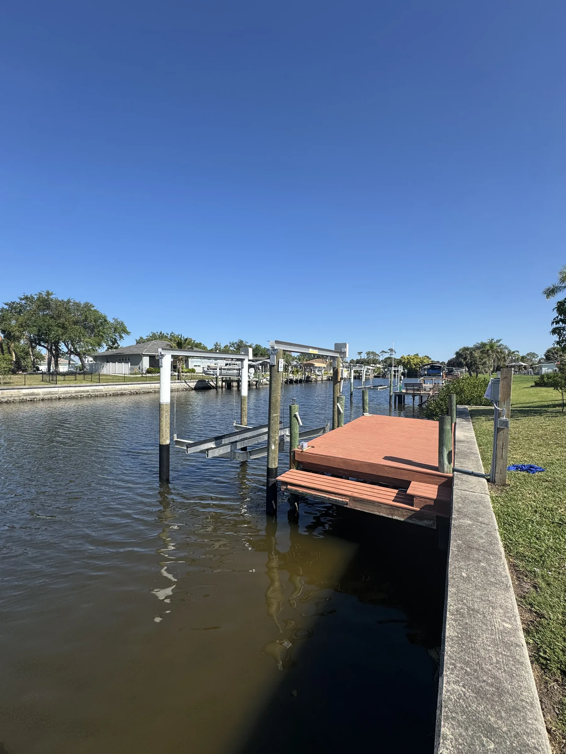 A red brown dock and boat lift beside a residential canal seawall