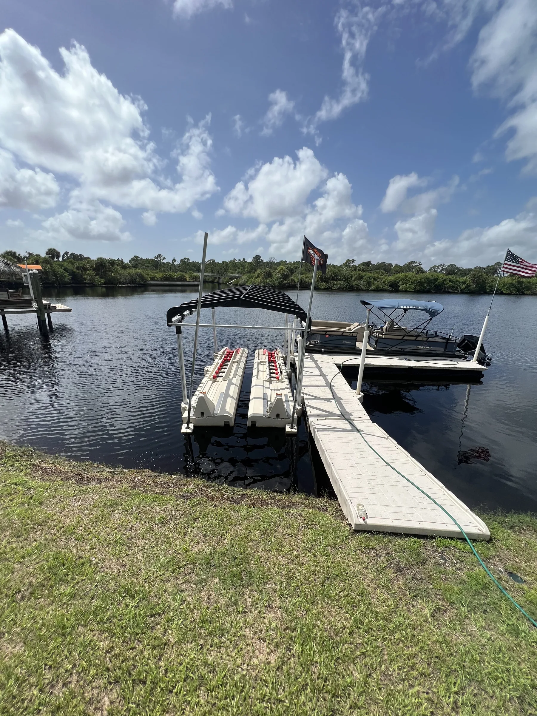 A floating dock beside personal watercraft ports and a pontoon boat