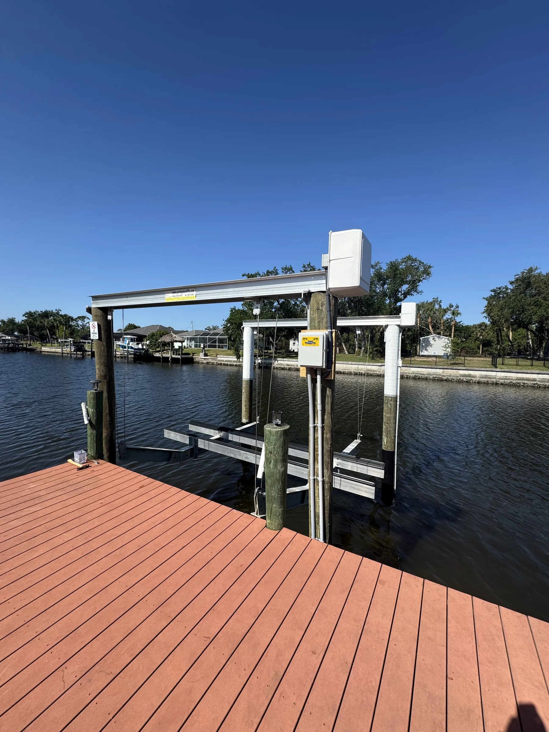 Boat lift beams and pilings beside red brown dock decking