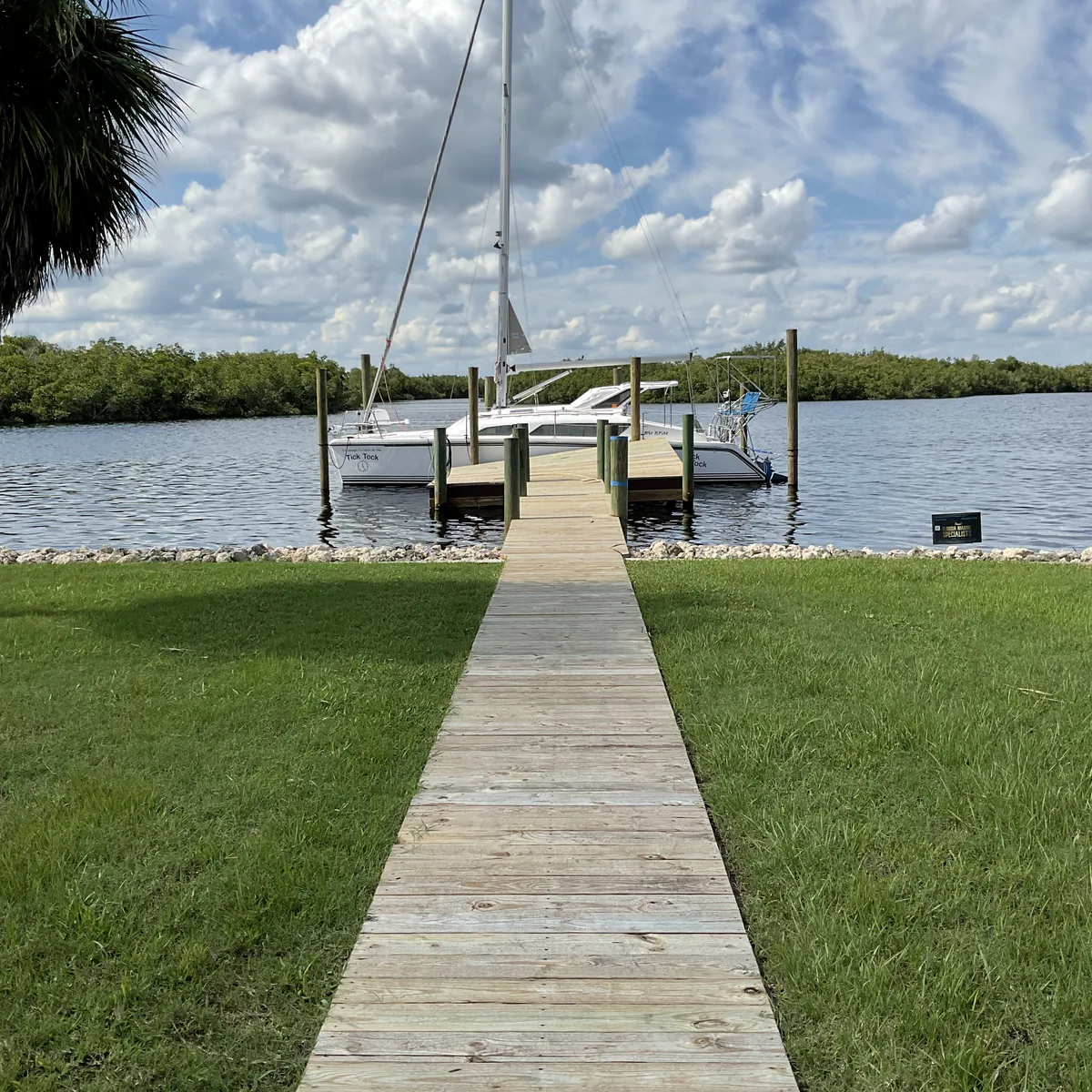 A timber walkway connecting a waterfront lawn to a boat lift