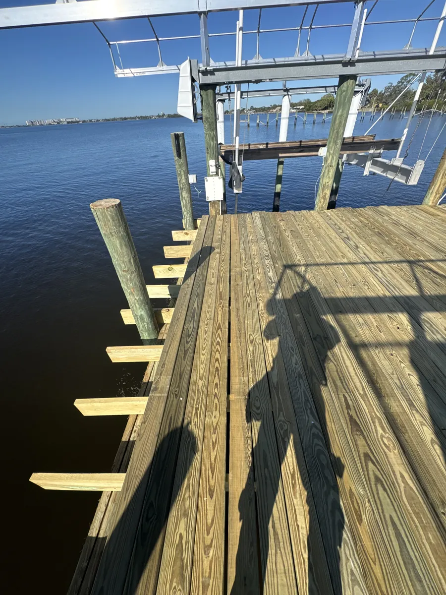 Timber dock surface beside boat lift equipment and exposed edge framing