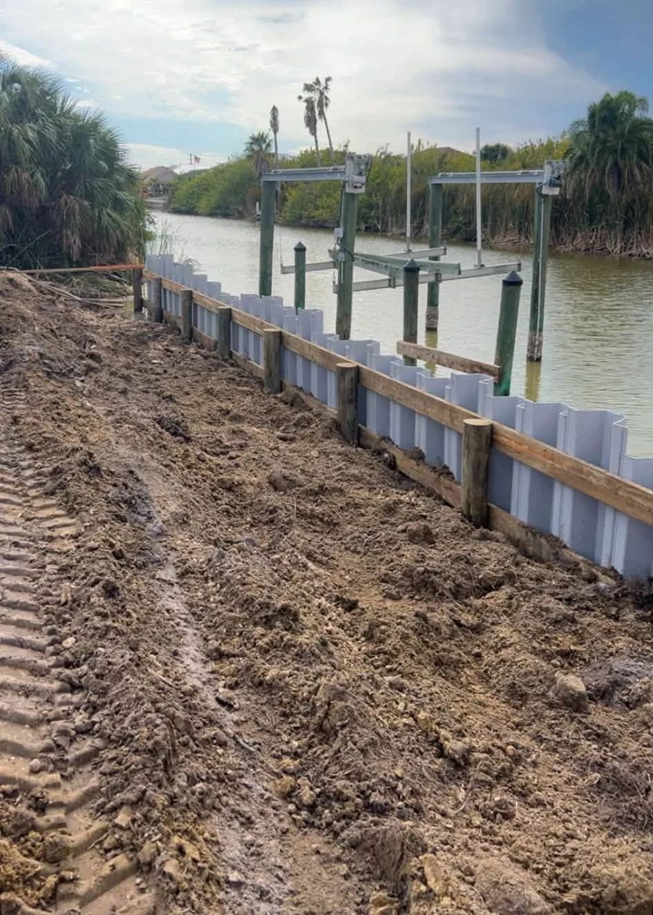 White vinyl sheet pile panels with timber bracing beside a canal